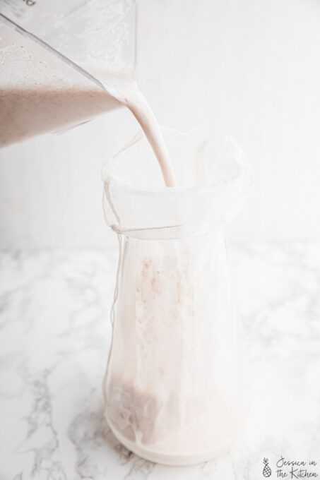 Pouring homemade almond milk into nut milk bag