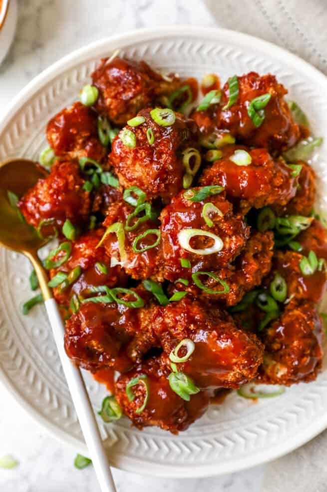 Bbq cauliflower wings on a plate with a spoon beside it.