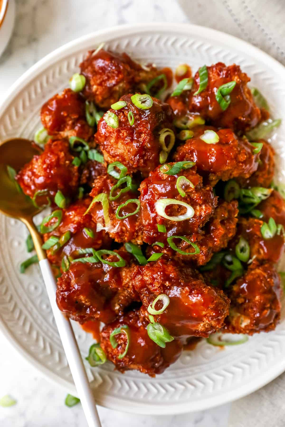 Bbq cauliflower wings on a plate with a spoon beside it.