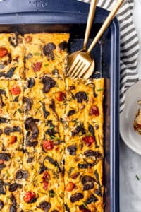 Vegan frittata in a baking sheet with fork and spoon in it.