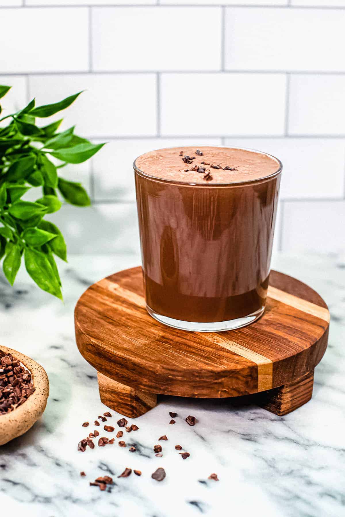 finished chocolate smoothie on a cutting board with cacao nibs around it