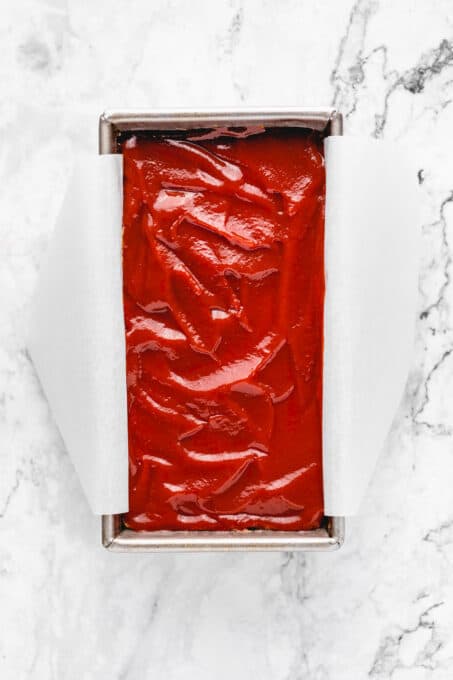 Overhead view of unbaked vegan meatloaf in a parchment-lined loaf pan.