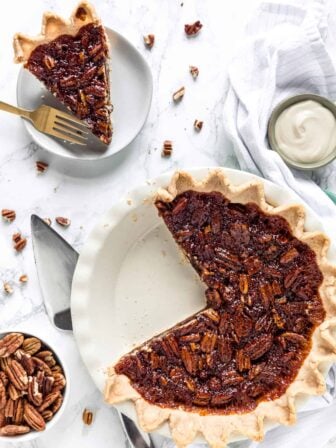 pecan pie with a slice on a plate and the rest of the pie in pie dish