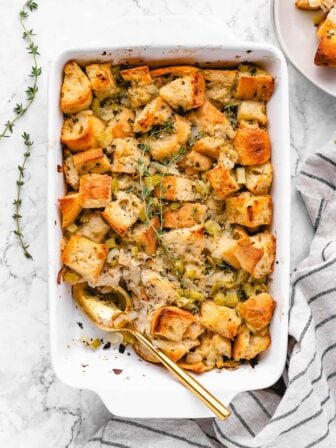 vegan stuffing in a casserole dish with a spoon and a scoop taken out
