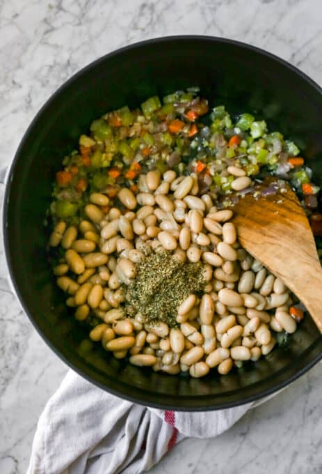 This hearty vegan white bean soup recipe is creamy and richly flavoured, perfect for keeping you warm and cozy. Only 15 minutes of prep time! adding in seasonings and white bean into the mirepoix