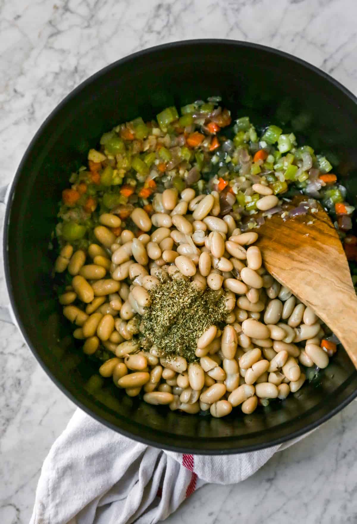 adding in seasonings and white bean into the mirepoix
