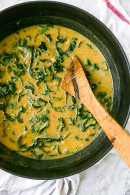 This hearty vegan white bean soup recipe is creamy and richly flavoured, perfect for keeping you warm and cozy. Only 15 minutes of prep time! White bean soup in pot with wooden spoon