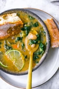 Bowl of white bean soup on plate with bread