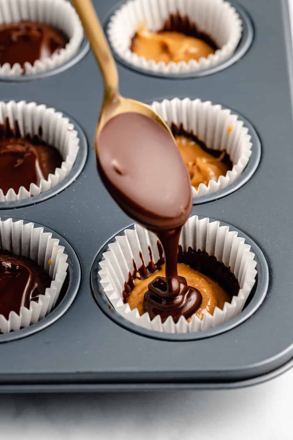 A Spoon Scooping the Top Layer of Chocolate Over the Peanut Butter