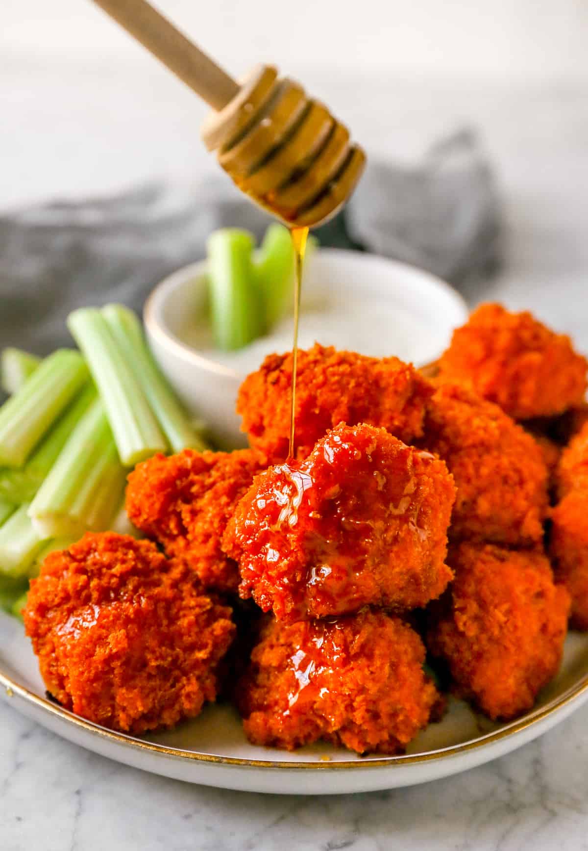buffalo cauliflower wings on a plate drizzled with maple syrup on a dripper