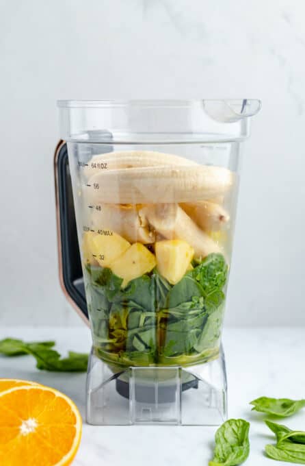Green smoothie ingredients in a blender before being blended