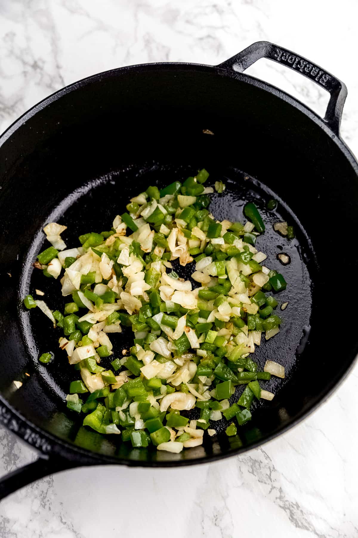 onions and bell peppers cooking in a cast iron skillet
