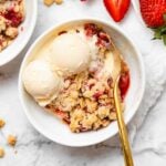 strawberry crisp in a bowl with ice cream and a spoon
