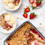 strawberry crisp in baking dish, two bowls with ice cream and strawberries on counter