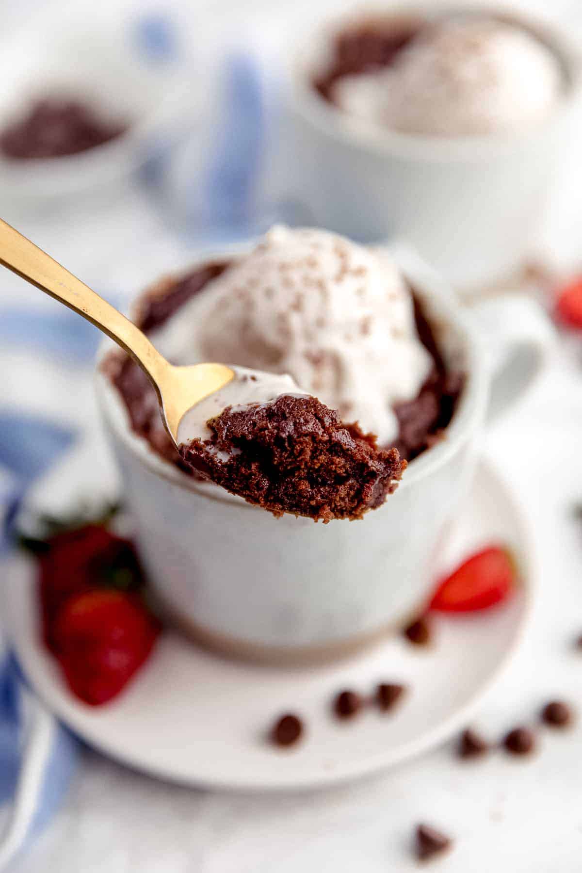Mug brownie with vanilla ice cream on a spoon.