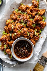 plate of cauliflower wings in a tray with sauce in a small bowl beside it