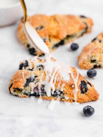 white glaze being drizzled onto a blueberry scone