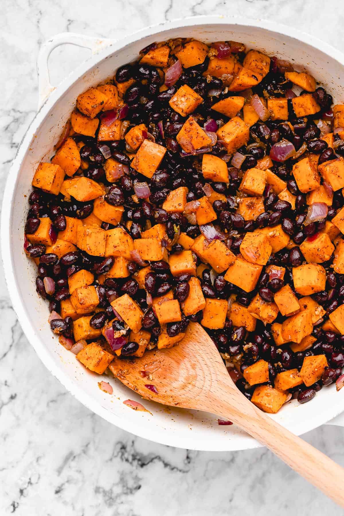 Chopped sweet potato with black beans in a pan.