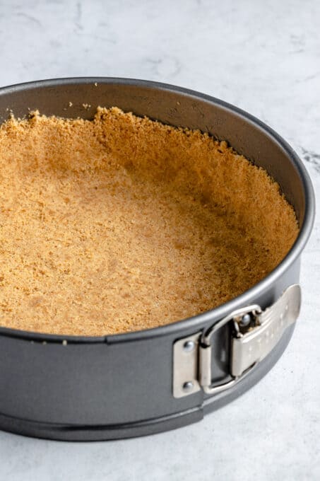 Pressed graham cracker crust in a springfrom pan.