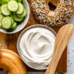 Plain cream cheese with bagels on a cutting board.