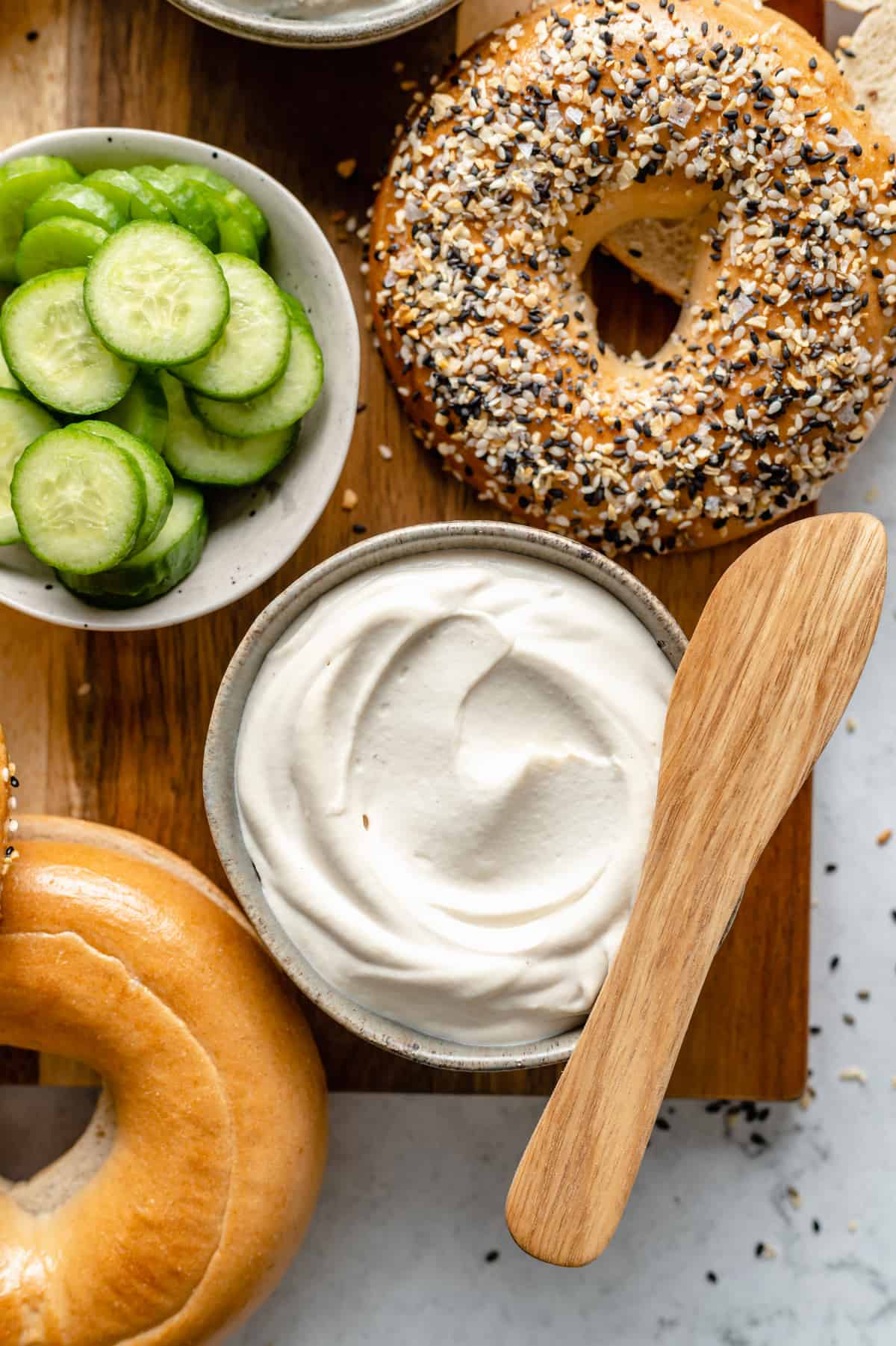 Plain cream cheese with bagels on a cutting board.