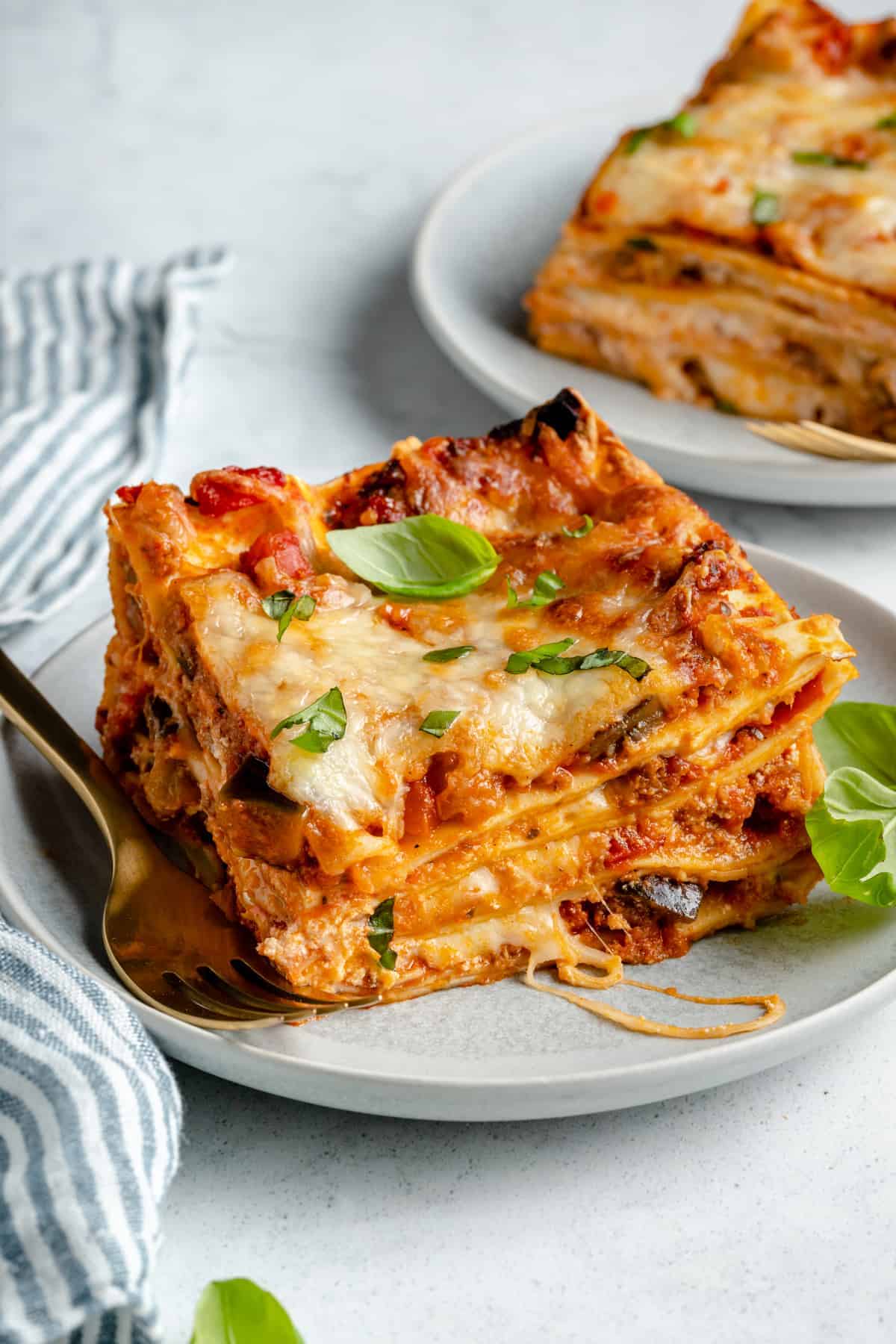 A plate of cheesy lasagna with basil.