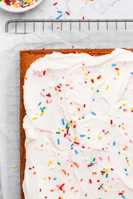 Sheet cake with whipped frosting and rainbow sprinkles.