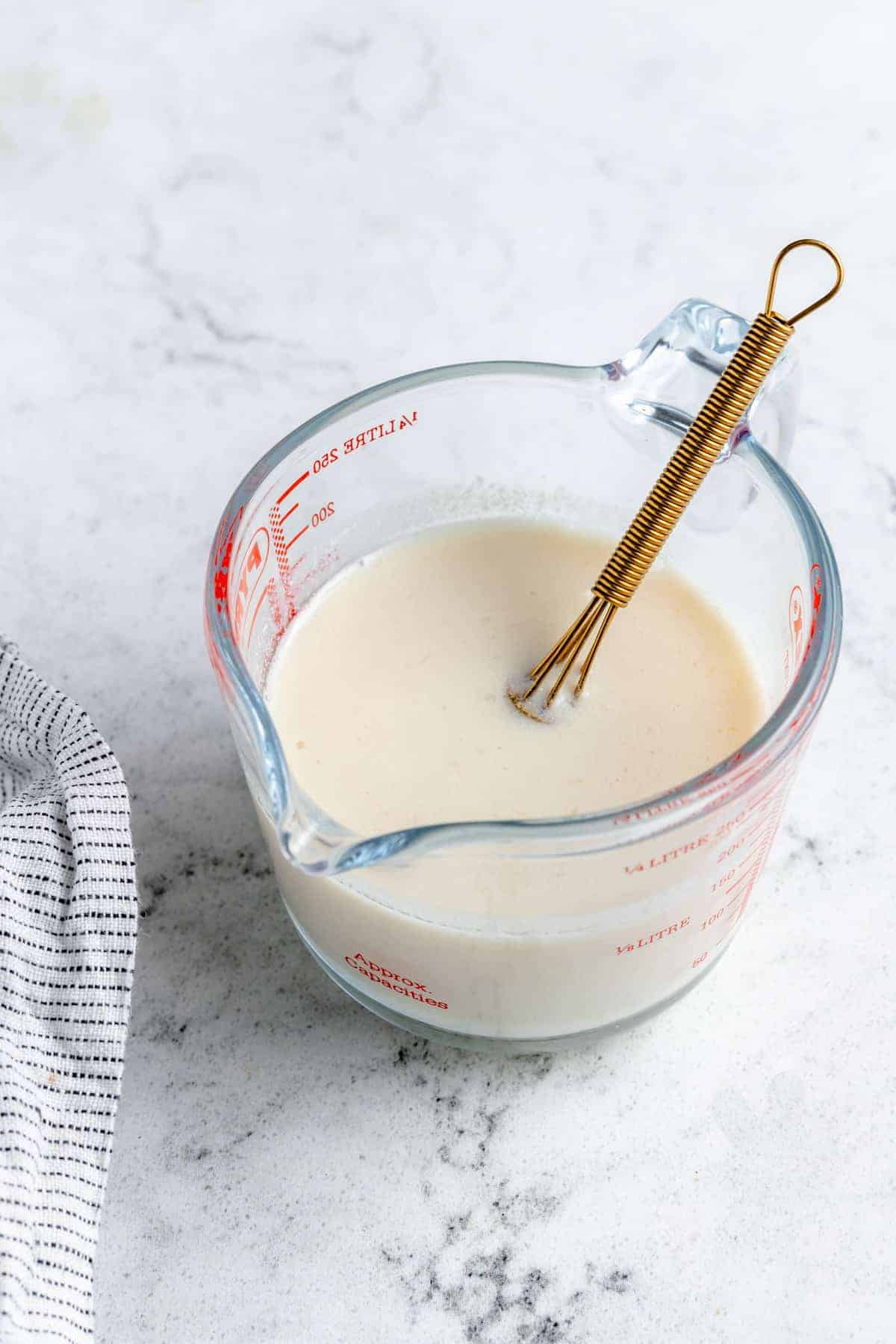 Whisked vegan buttermilk in a measuring cup.