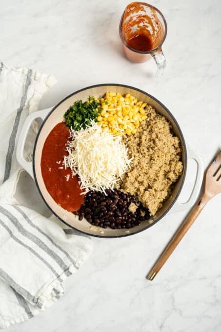 Corn, black beans, quinoa, marinara sauce, and cheese in a pan.
