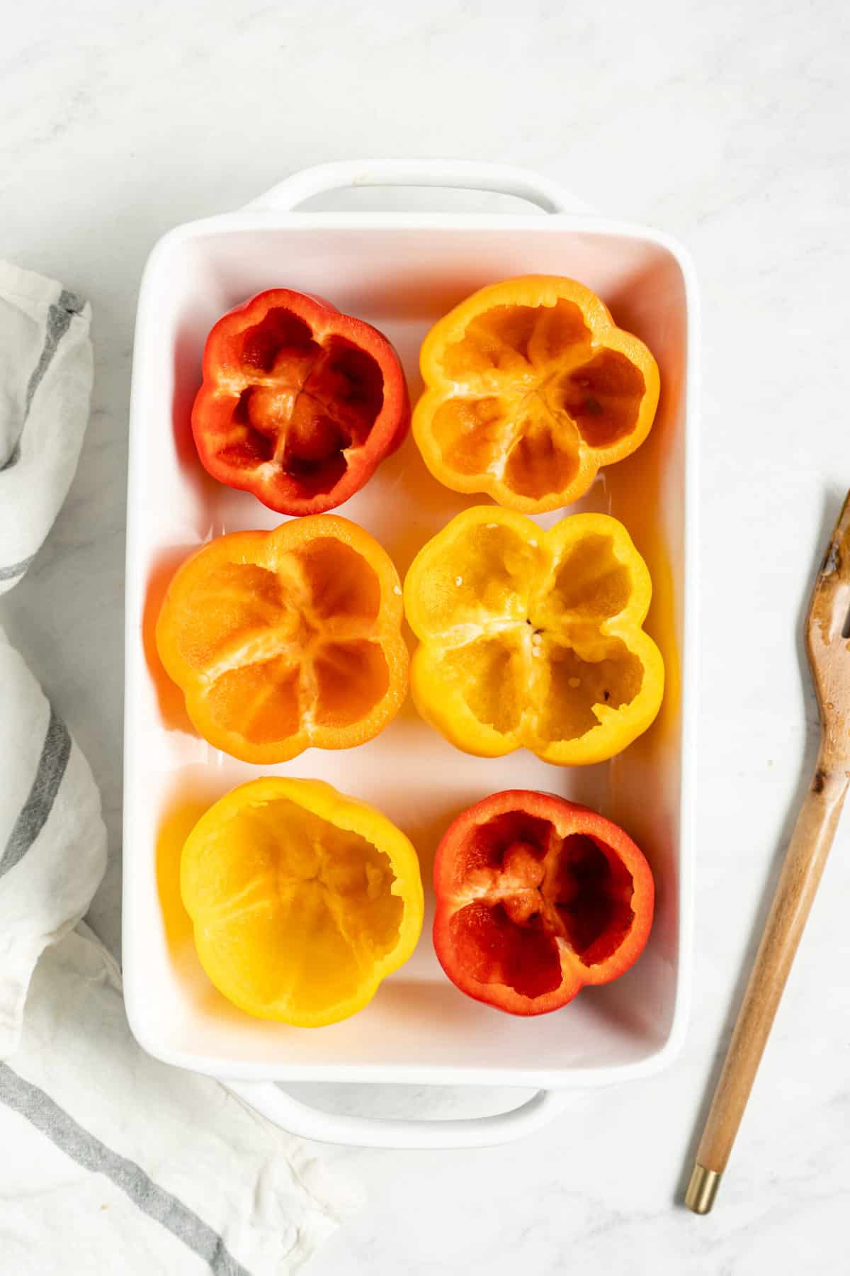 Scooped-out bell peppers in a baking dish.
