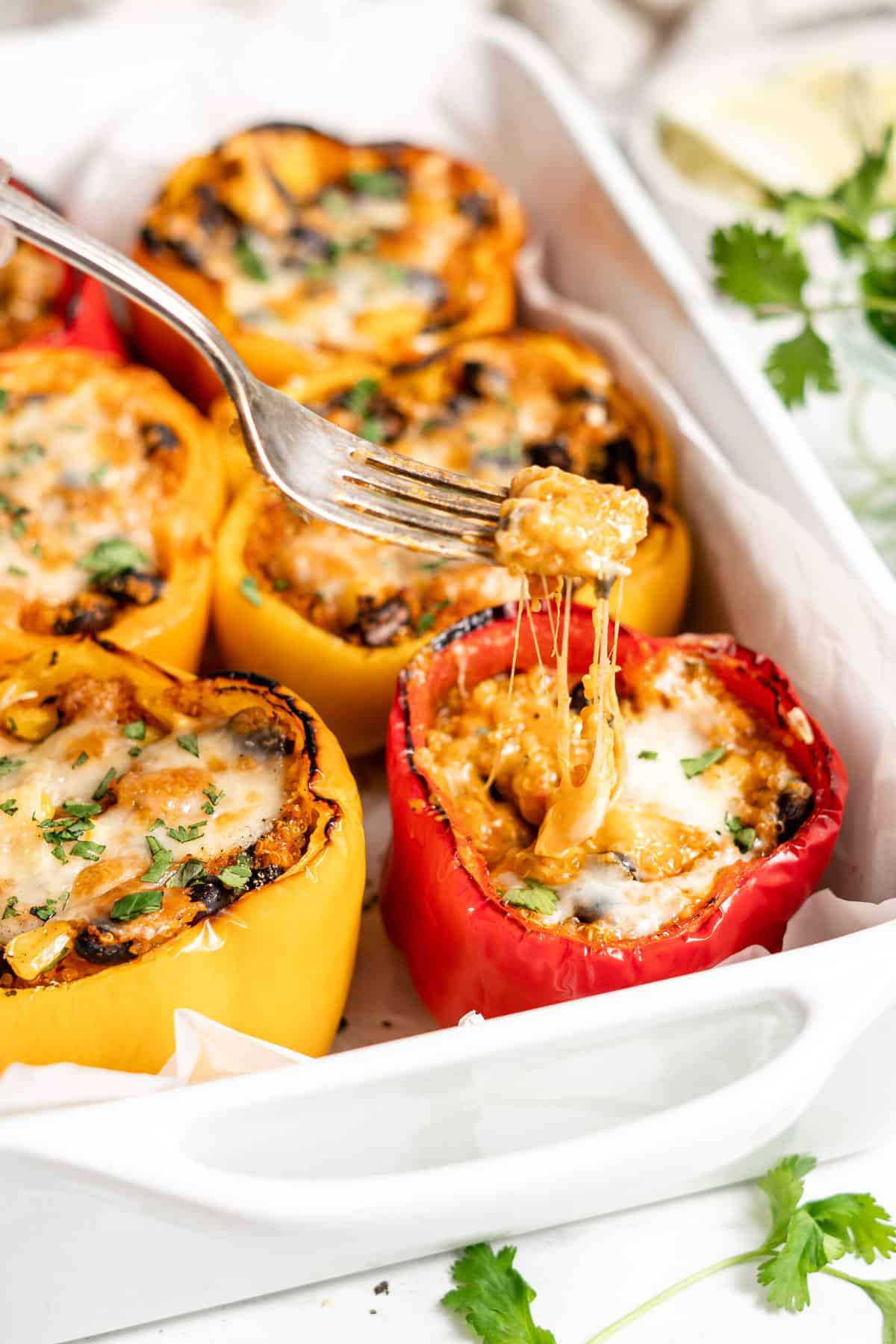Vegan stuffed peppers in a baking dish with mozzarella cheese.