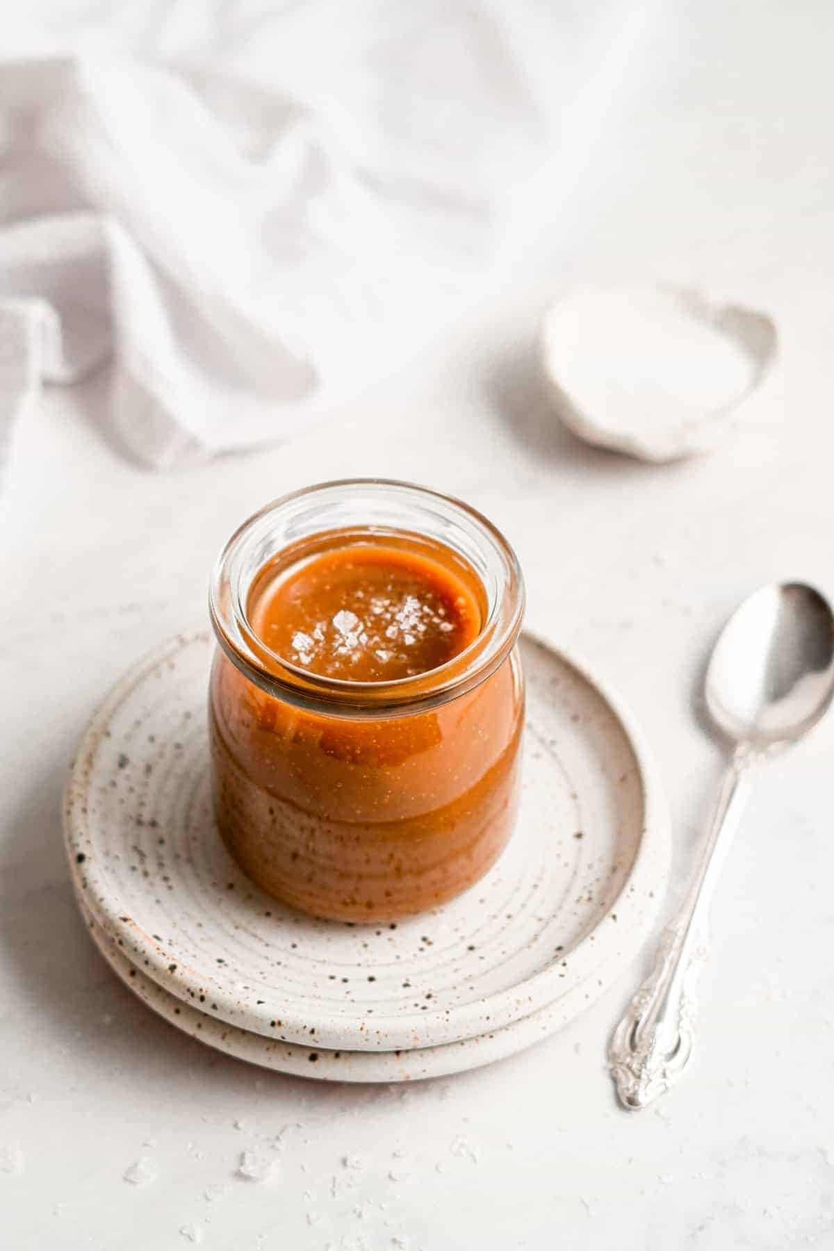 A jar of vegan caramel sauce on a plate.