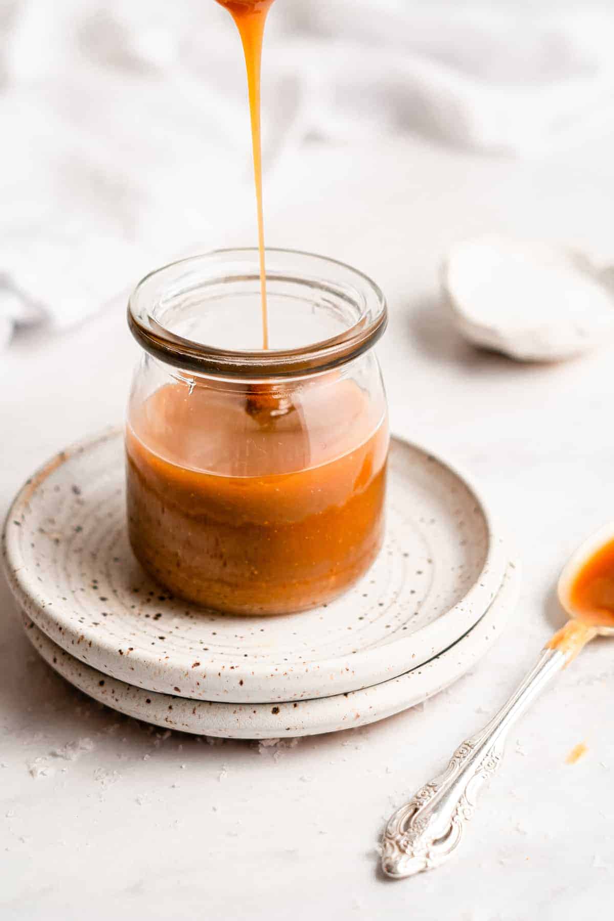 Caramel sauce drizzling into a jar.