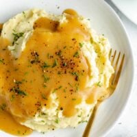 Overhead shot of mashed potatoes on white plate topped with gravy