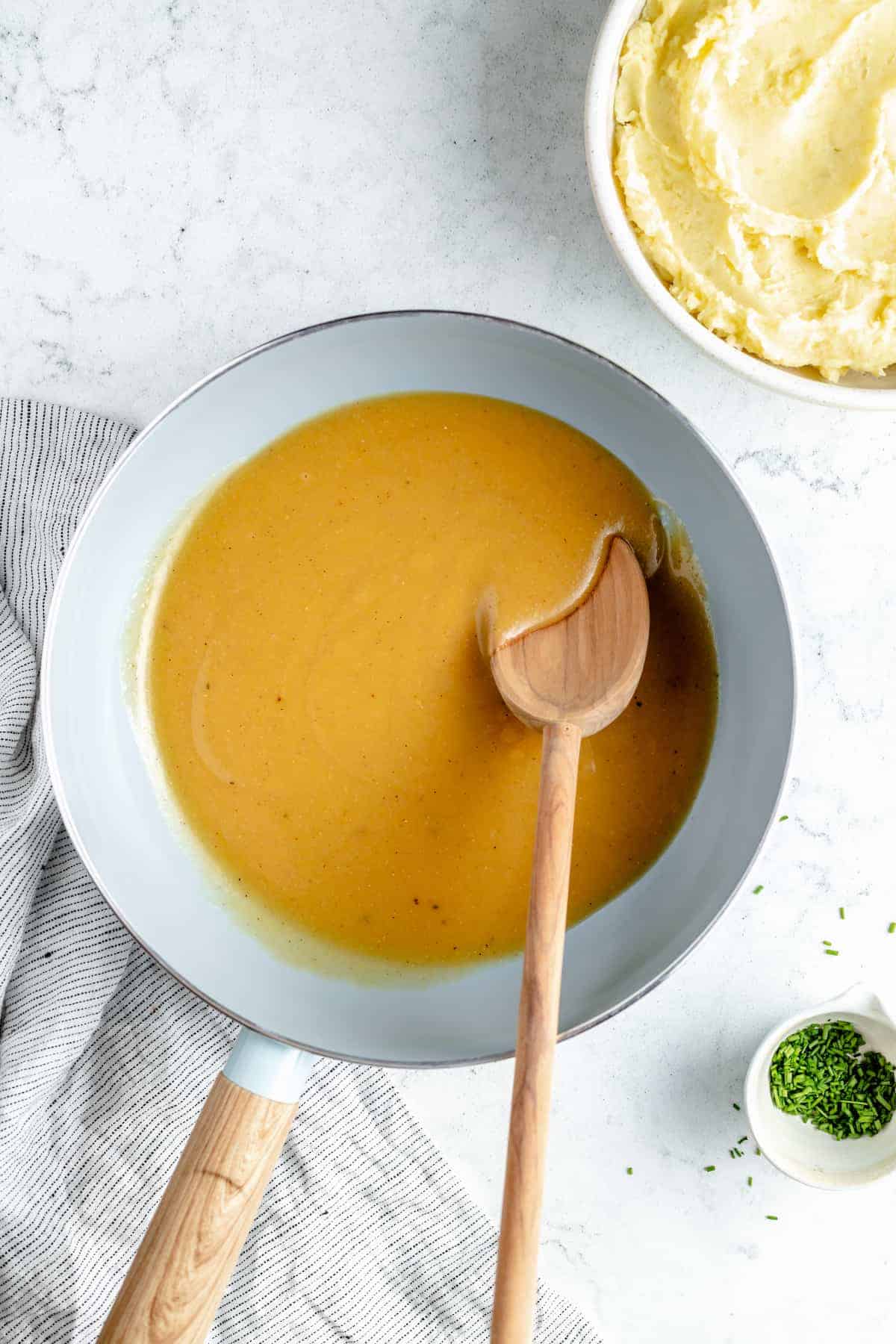 Vegan gravy in saucepan with wooden spoon