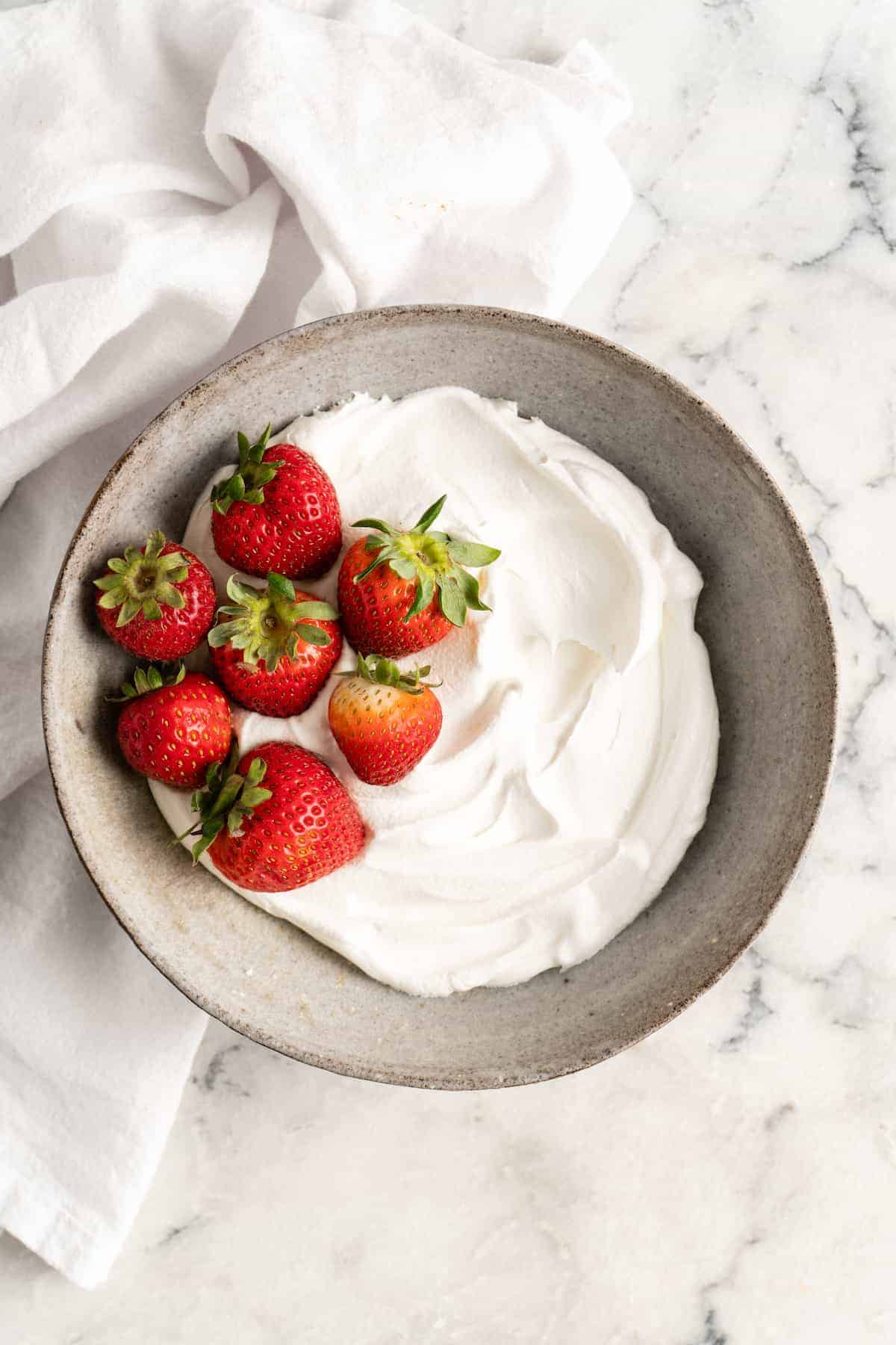 Overhead shot of bowl of vegan whipped cream and strawberries