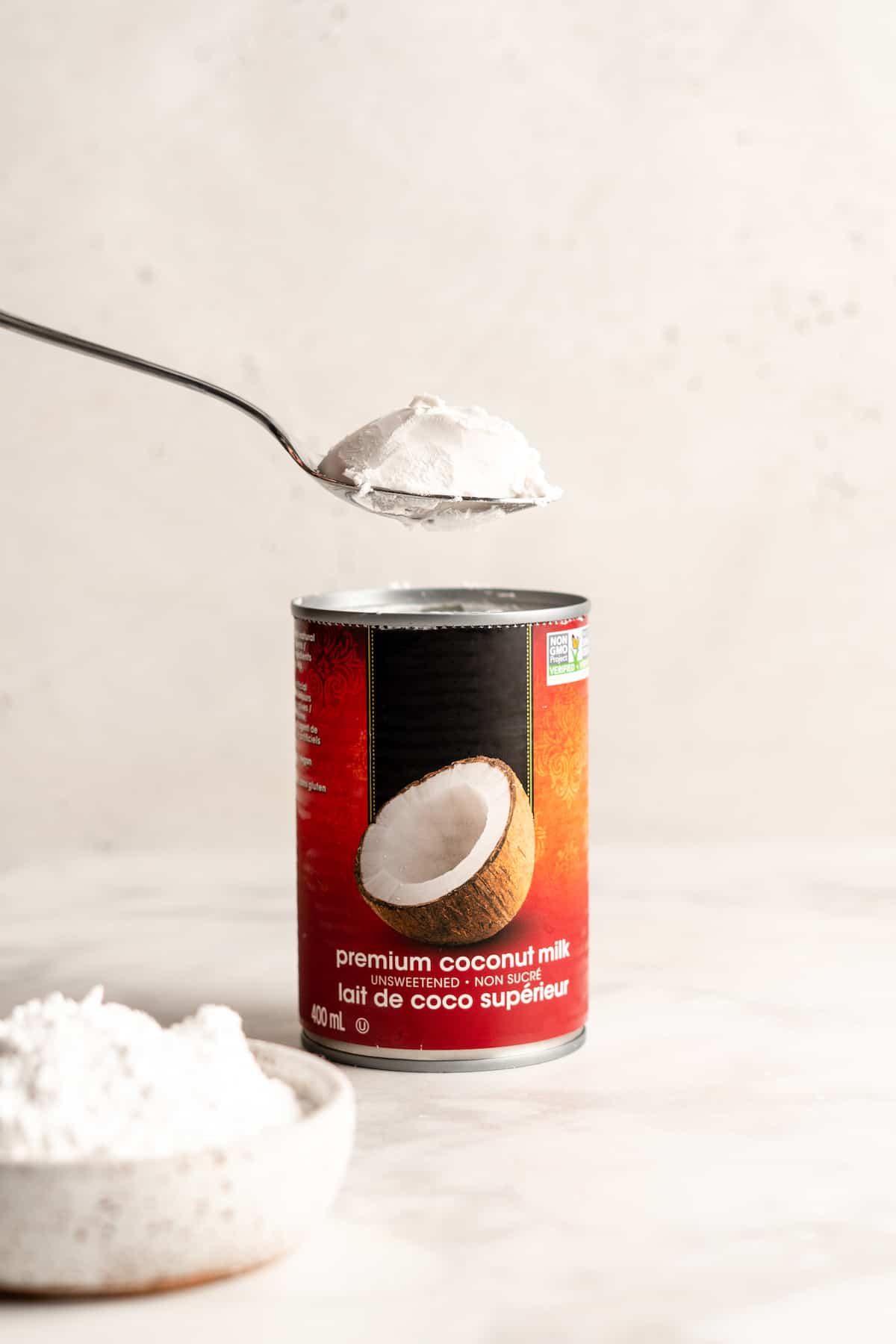 Spoonful of coconut cream being removed from coconut milk