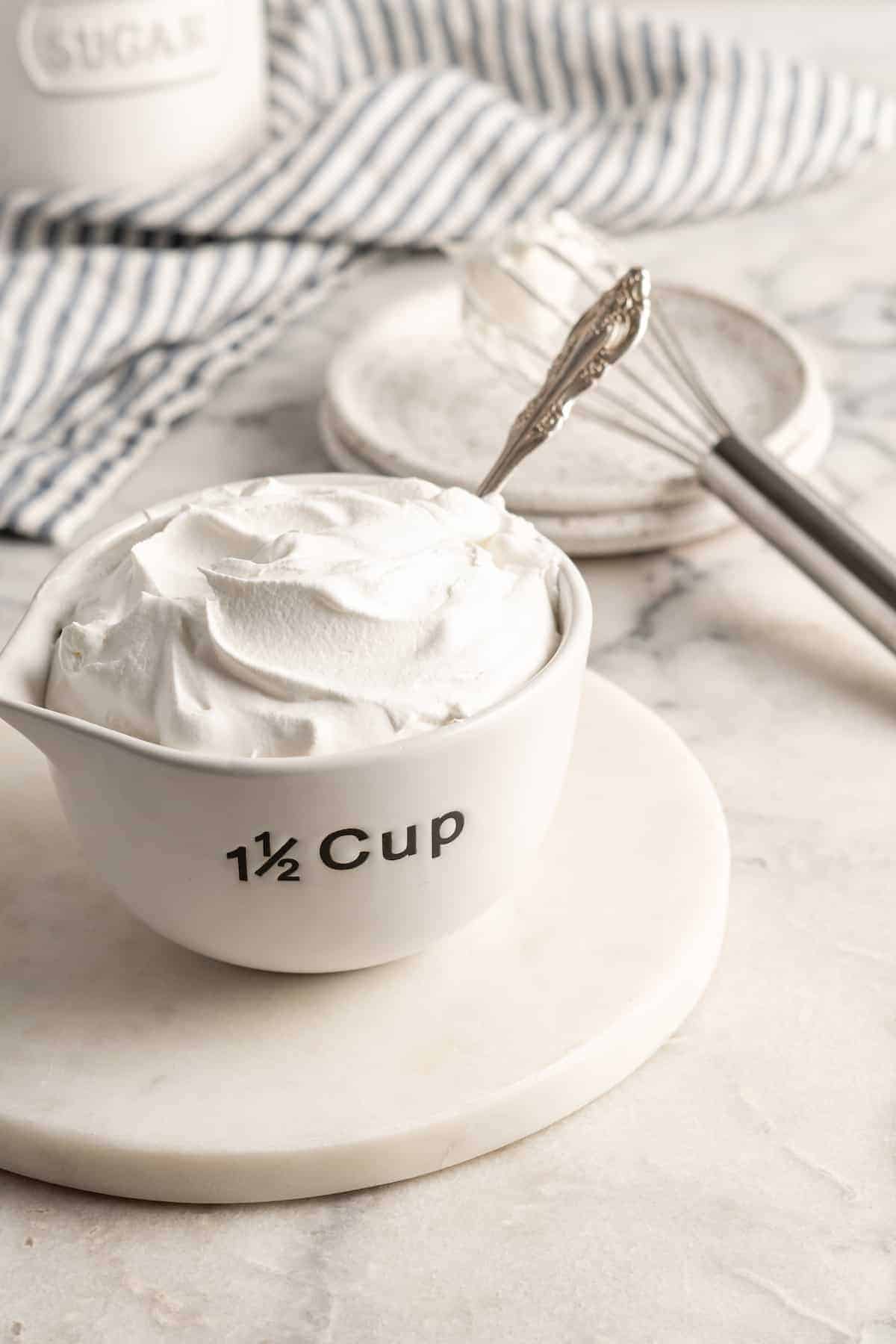 White measuring cup filled with vegan whipped cream