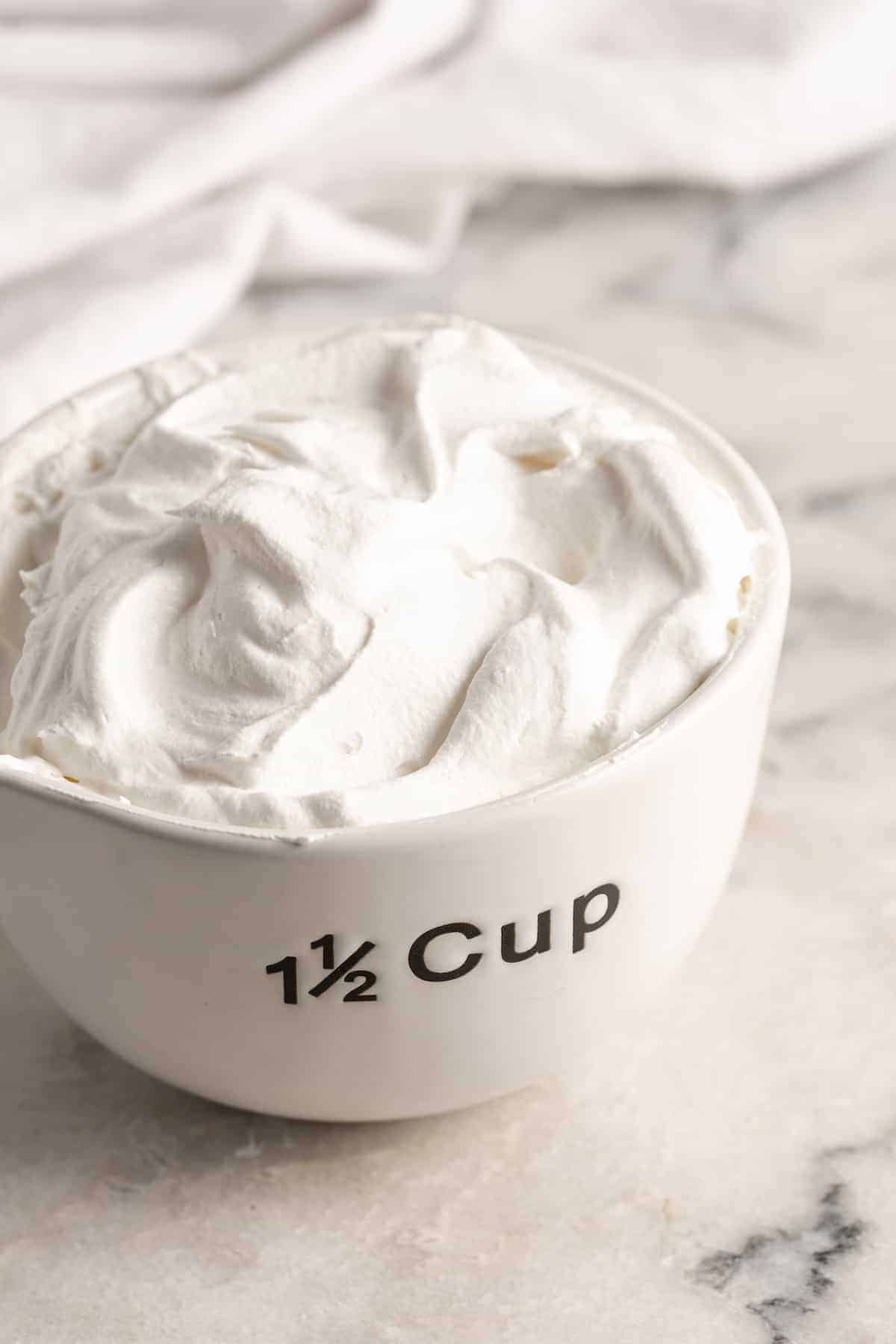 Measuring cup filled with whipped coconut cream