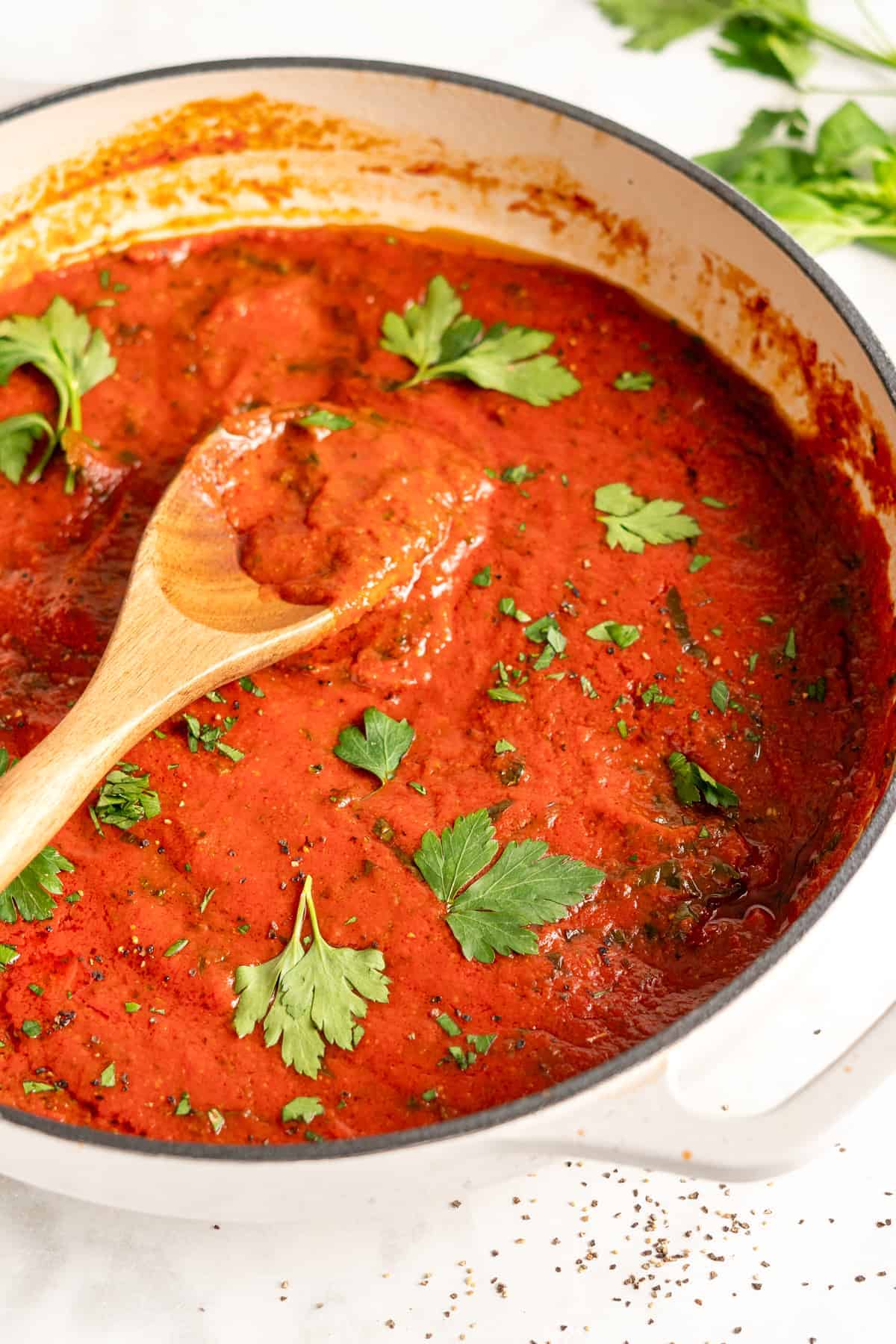 Homemade marinara sauce in white pot with wooden spoon