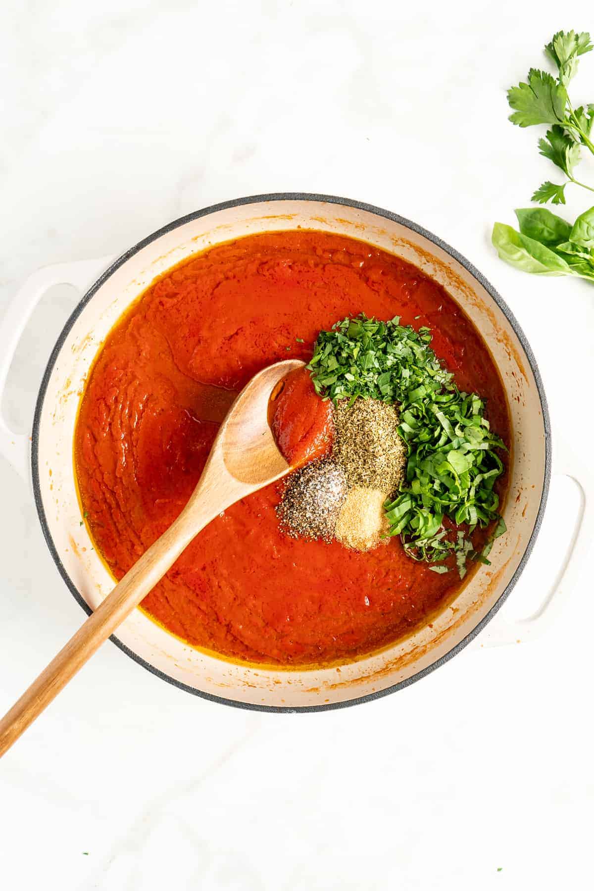 Overhead view of marinara sauce in pot with seasonings about to be stirred in