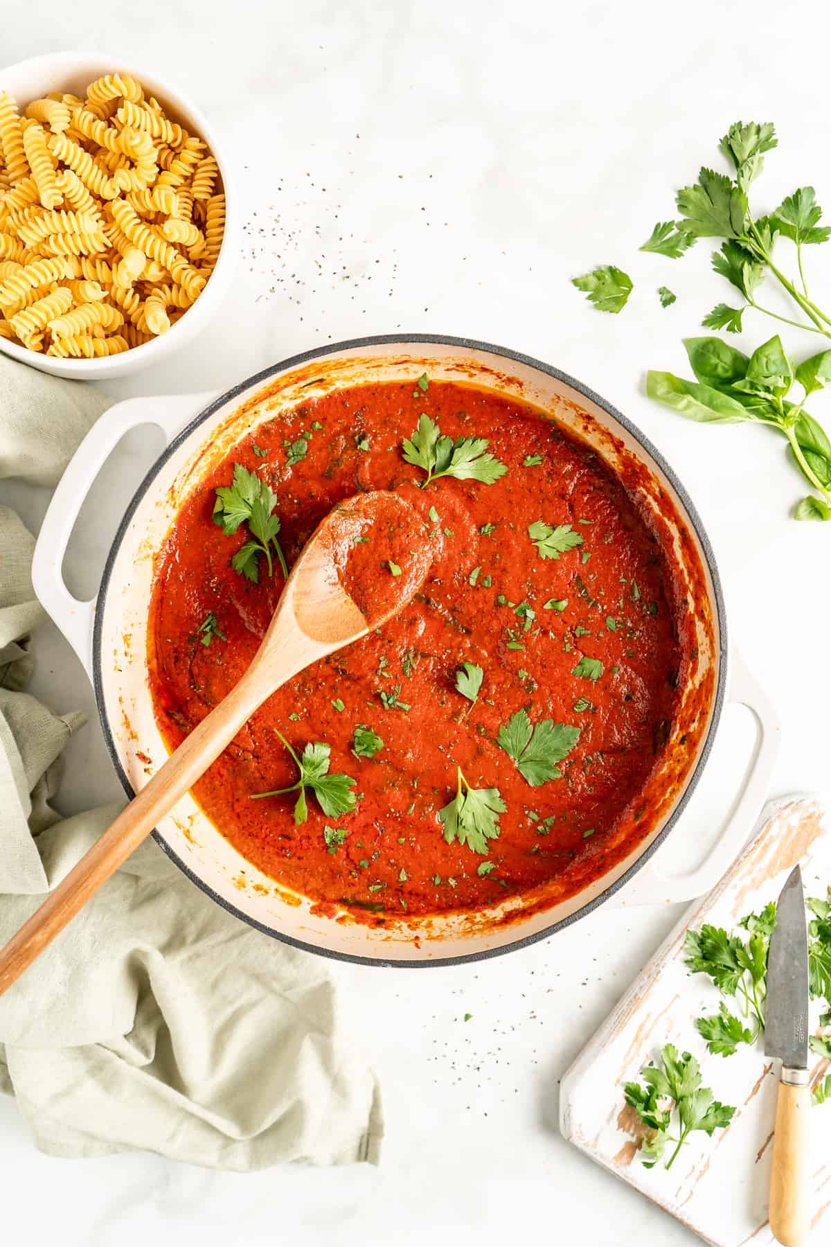 Overhead view of homemade marinara sauce in pot with parsley leaves scattered on top