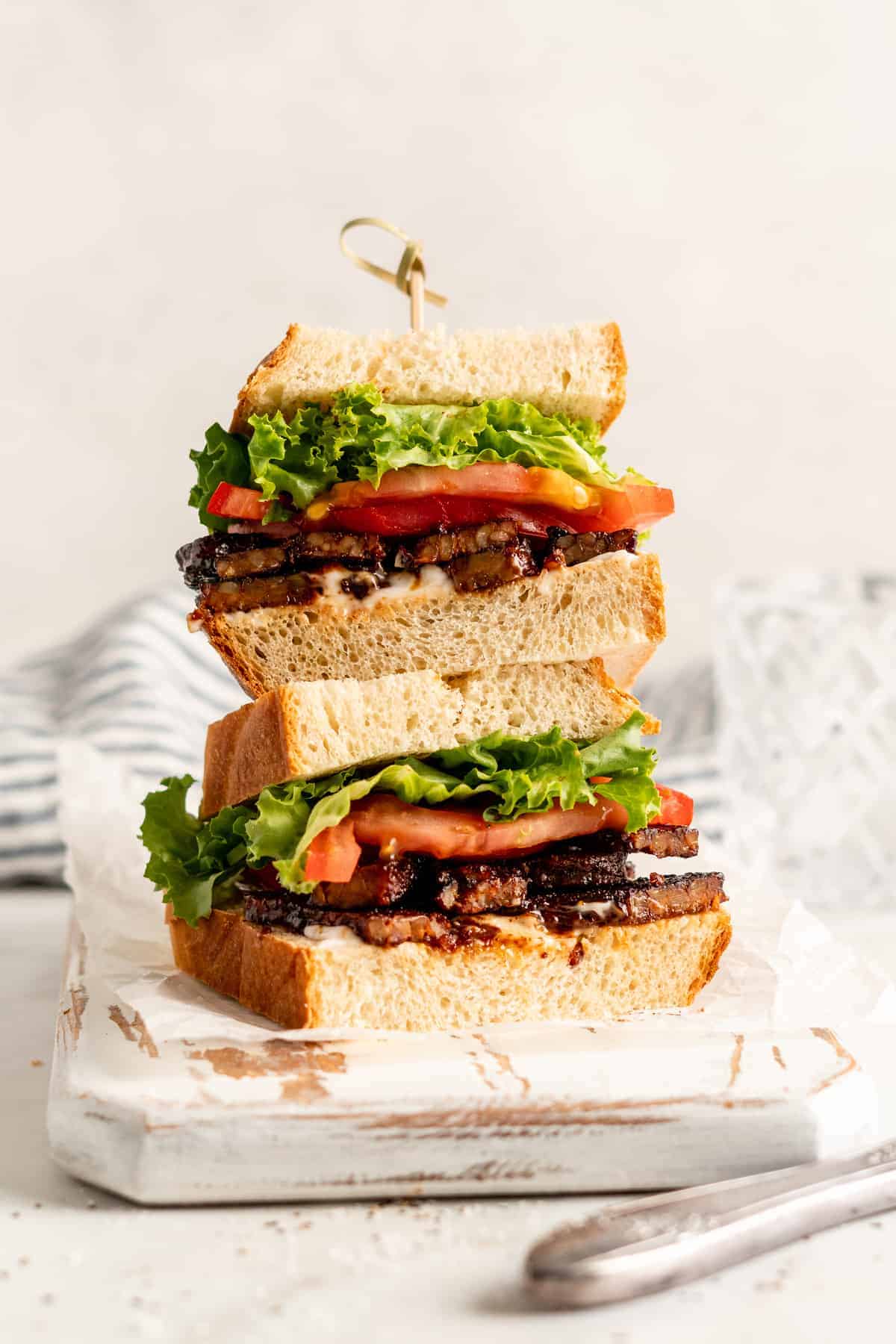 Two halves of a TLT sandwich stacked on a cutting board