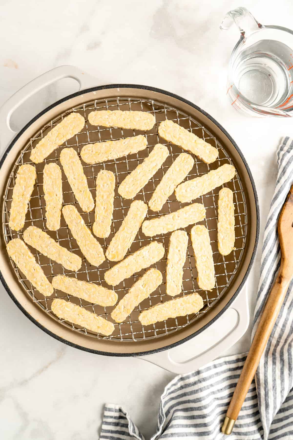 Tempeh slices being steamed in a Dutch oven