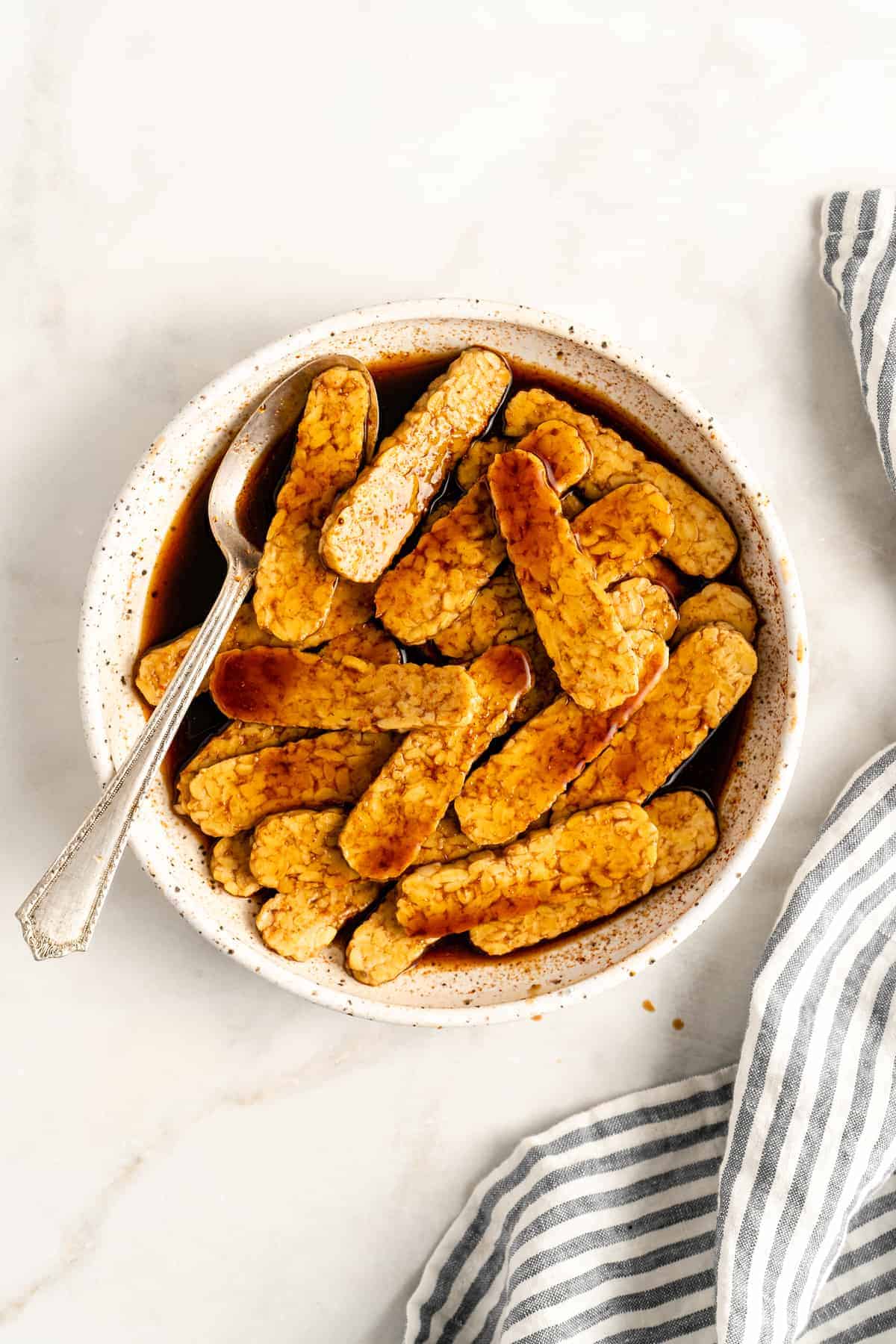 Bowl of tempeh slices being marinated