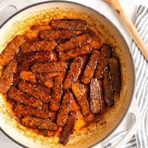 Overhead view of tempeh bacon slices being cooked in Dutch oven