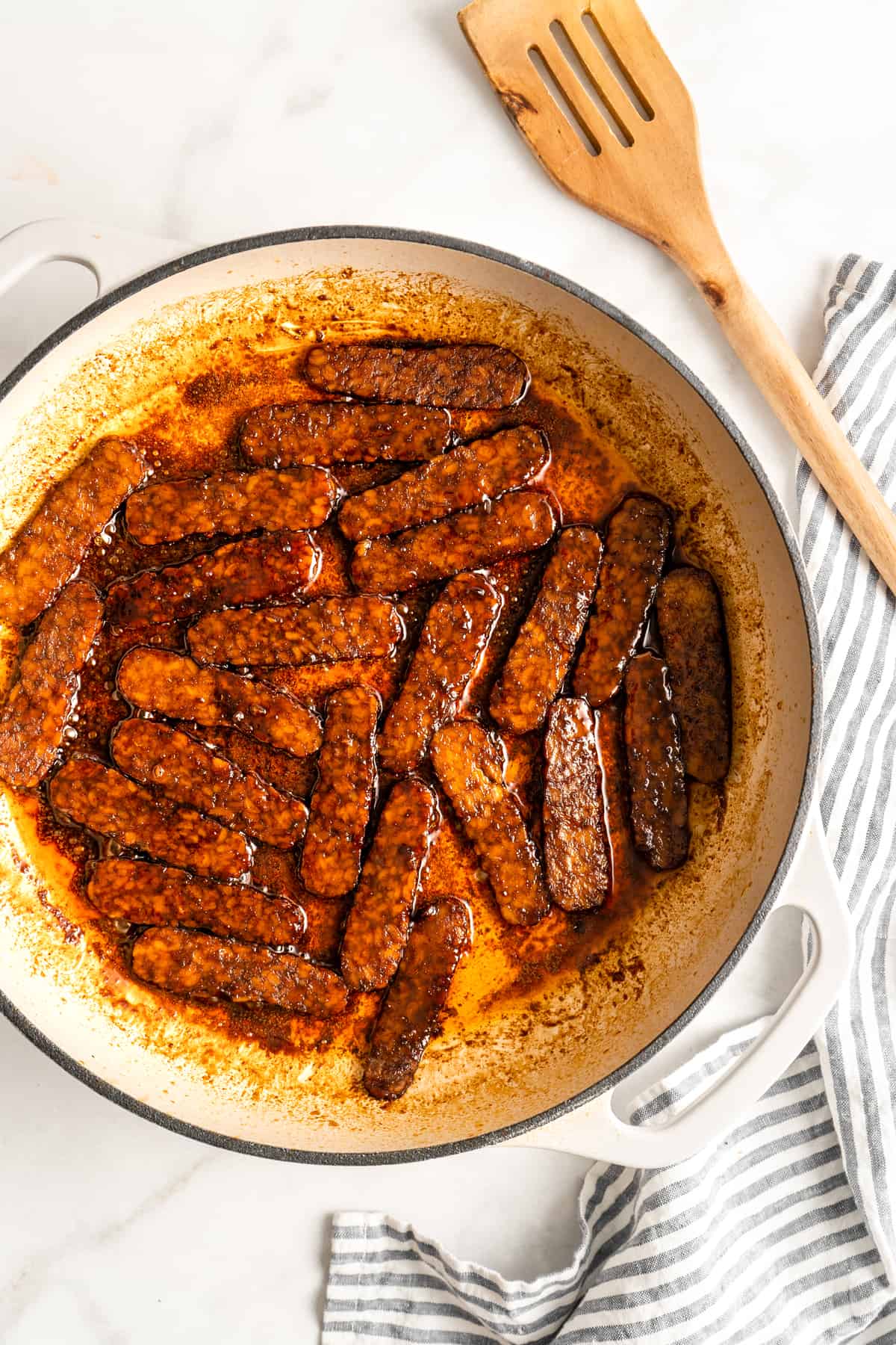 Overhead view of tempeh bacon slices being cooked in Dutch oven