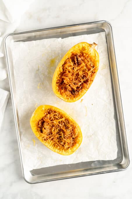 Overhead view of two spaghetti squash halves stuffed with lasagna