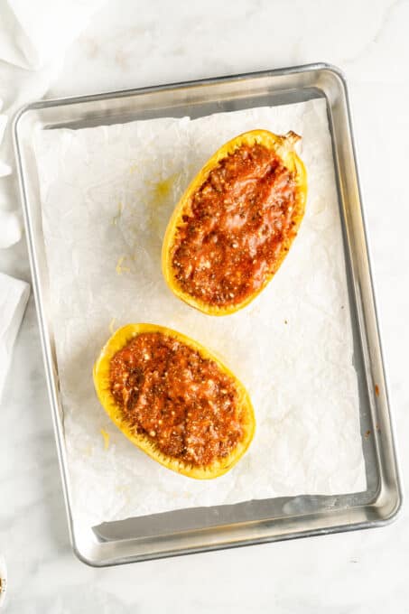 Overhead view of two spaghetti squash halves stuffed with lasagna filling