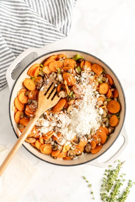 Carrots, mushrooms and other veggies in a pot with flour